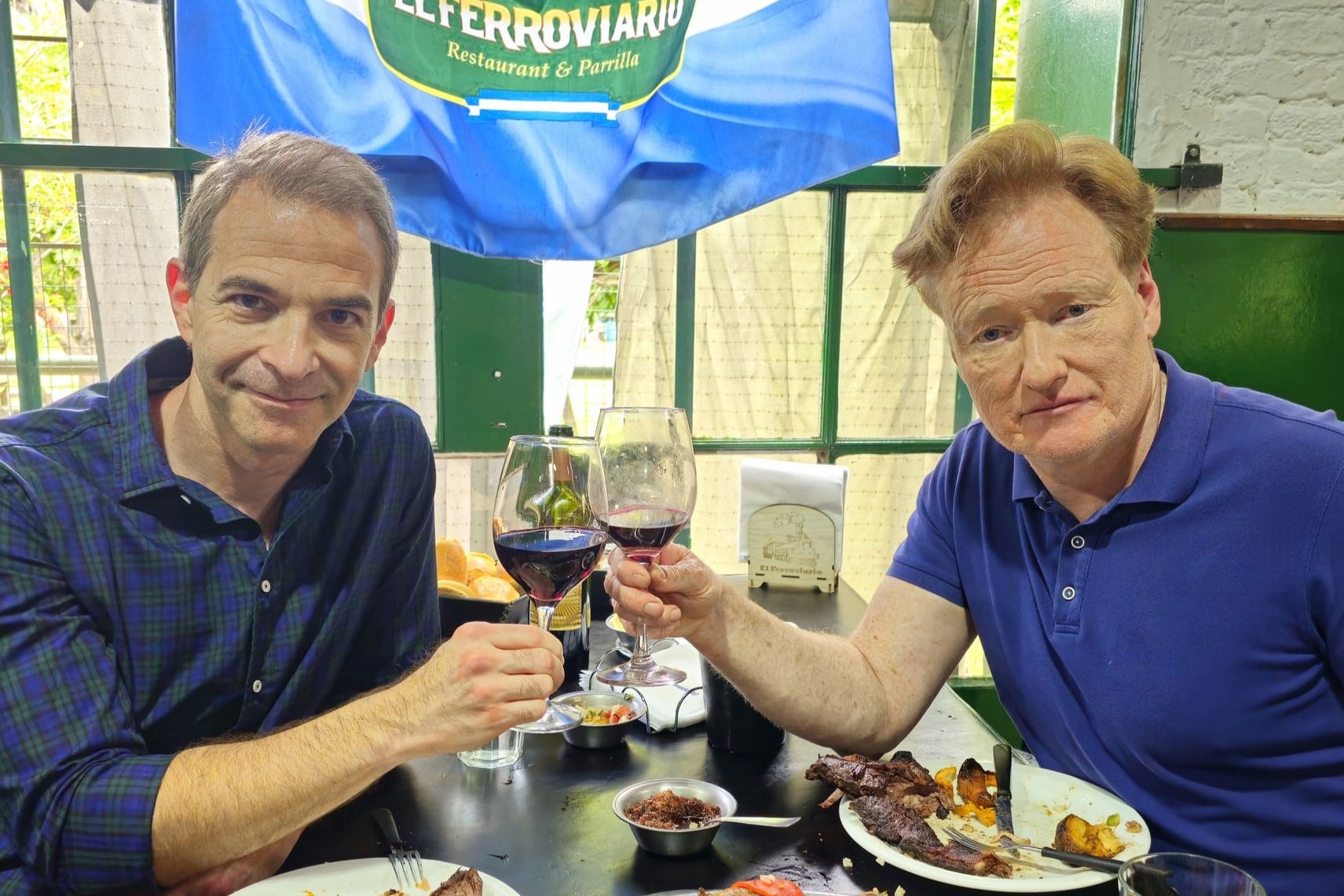 O'Brien (derecha) choca su copa junto al productor Jordan Schlansky en una parrilla de Liniers. Imagen: Twitter @ConanOBrien.