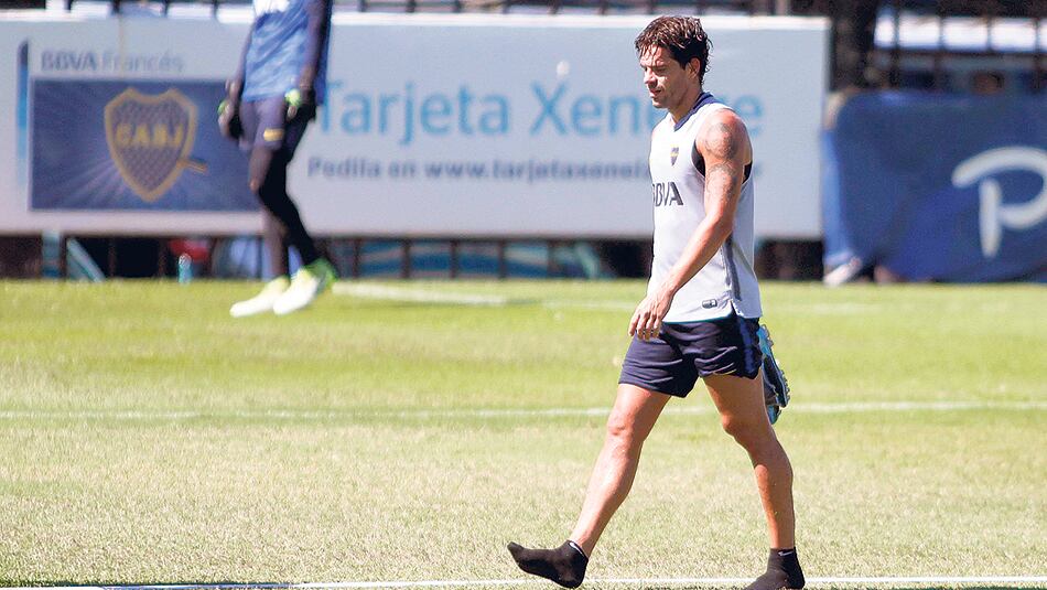 Gago caminando la cancha principal del complejo Pedro Pompilio con los botines en la mano.