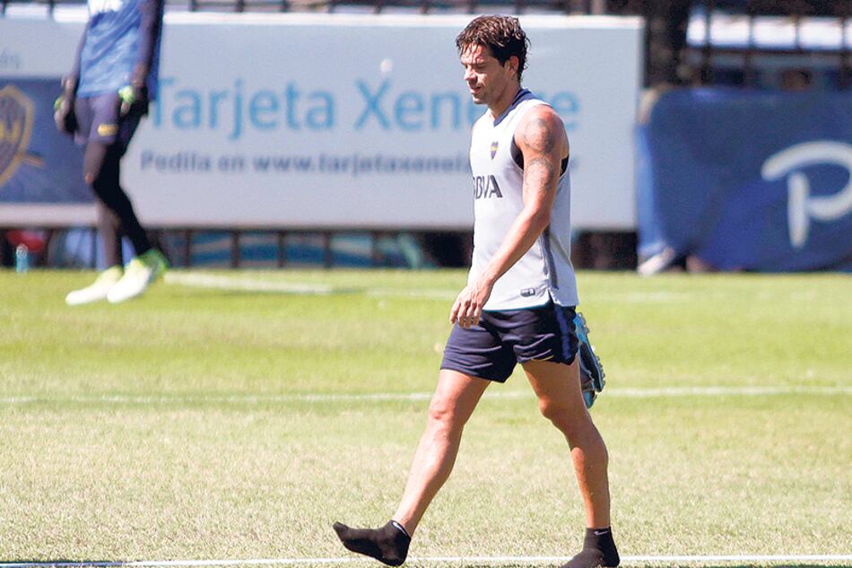 Gago caminando la cancha principal del complejo Pedro Pompilio con los botines en la mano.