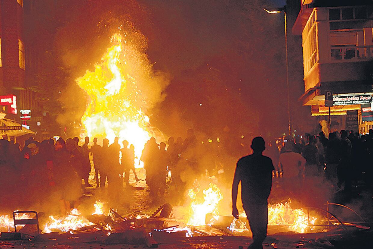Manifestantes caminan entre barricadas incendiadas en el distrito de Schanzenvietel, de Hamburgo, Alemania.