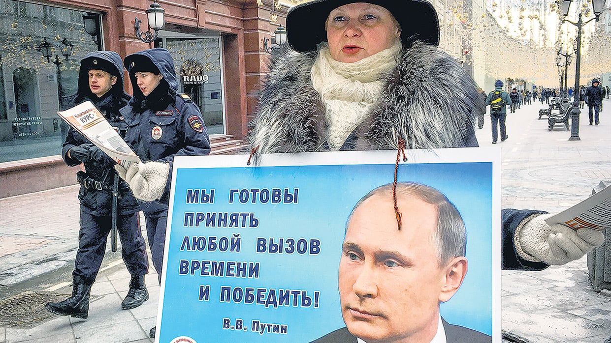 Una activista distribuye panfletos que promueven el voto a Putin ayer en el centro de Moscú, a horas de las elecciones.