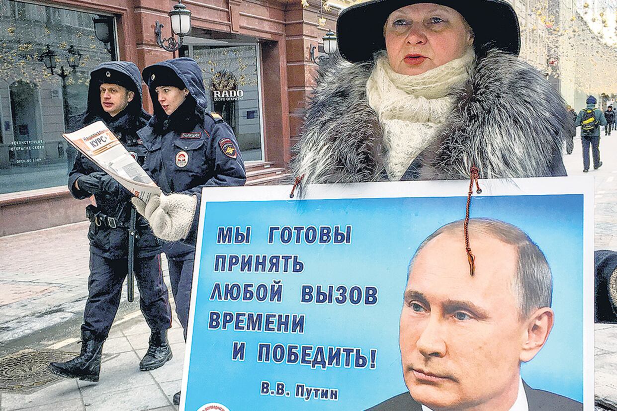 Una activista distribuye panfletos que promueven el voto a Putin ayer en el centro de Moscú, a horas de las elecciones.