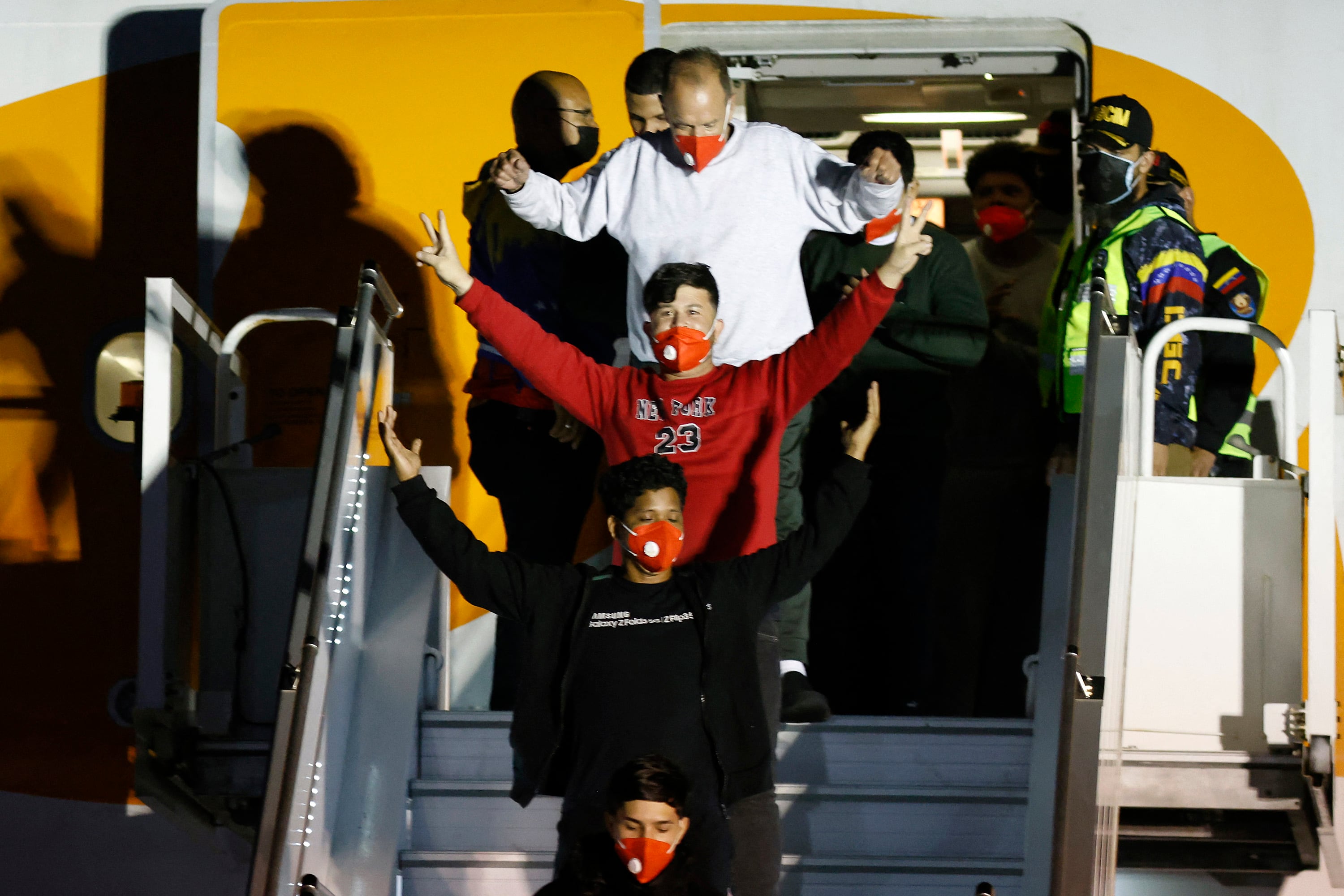 Migrantes venezolanos deportados saludan al descender de un avión en el aeropuerto Simón Bolívar