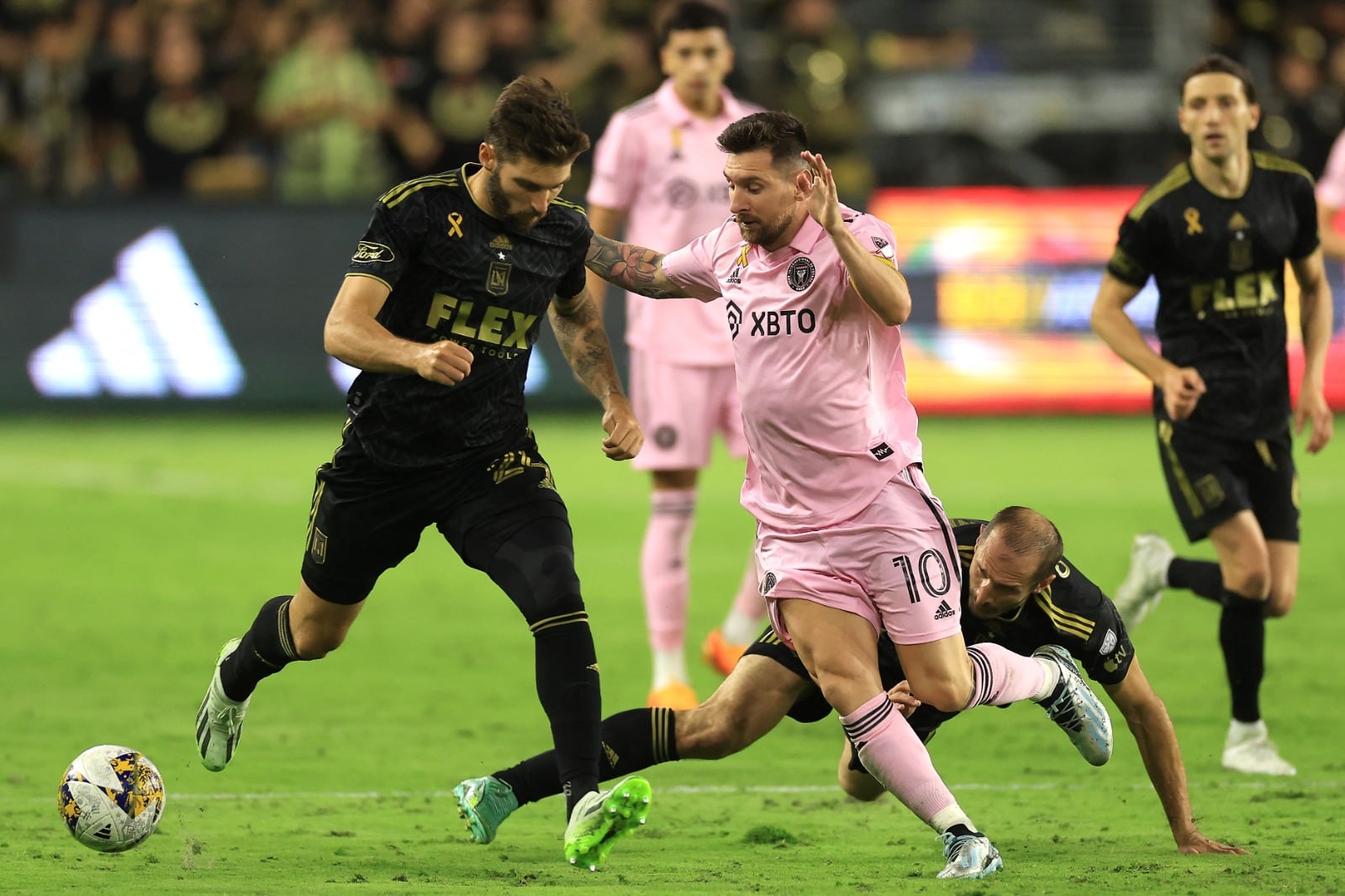 Messi maniobra ante los defensores de LAFC, mientras Chiellini mira desde el piso