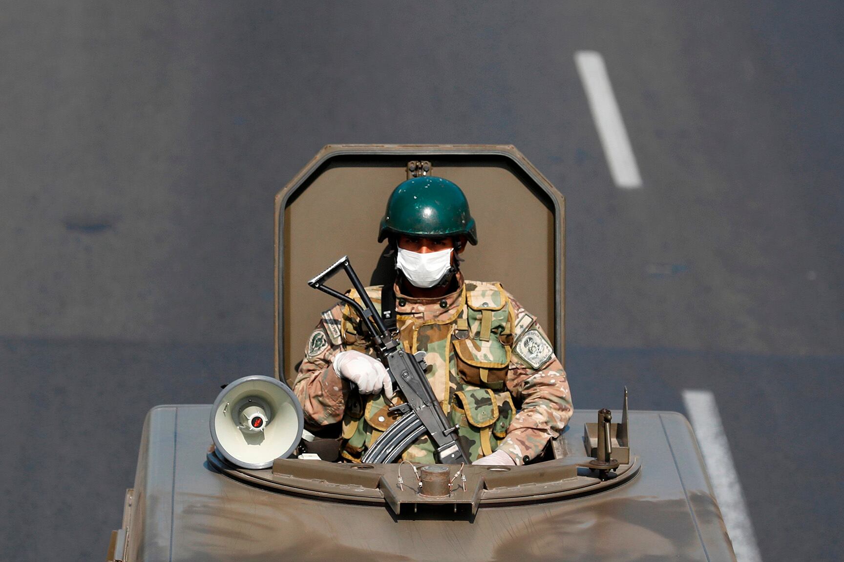 Un militar peruano patrulla las calles de Lima con barbijo, autoparlante y fusil automático. 