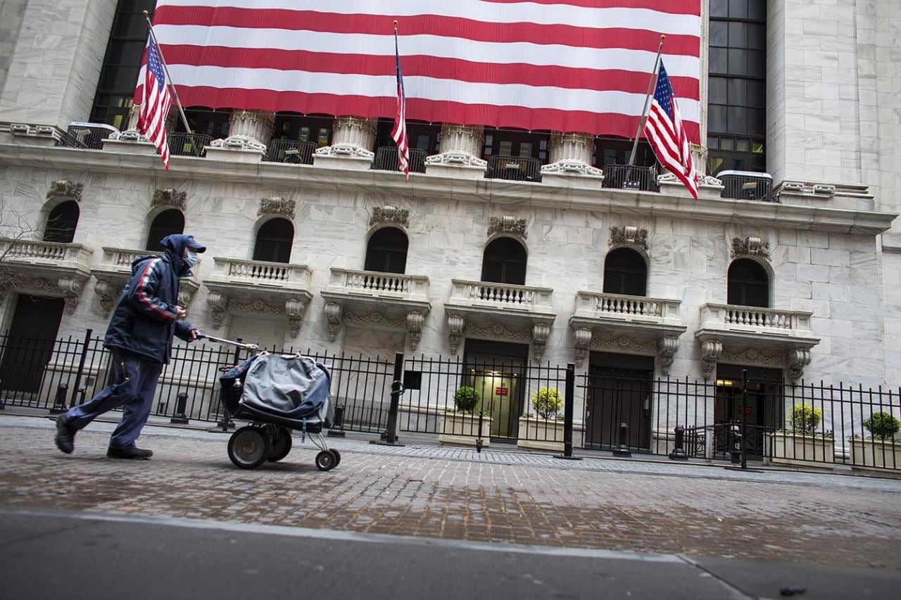 Un hombre empuja un carrito frente a la Bolsa de Comercio de Nueva York.  