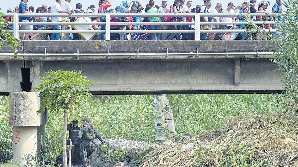 Policías vigilan el puente internacional Simón Bolívar que une Cúcuta con Táchira, mientras una marea humana cruza.