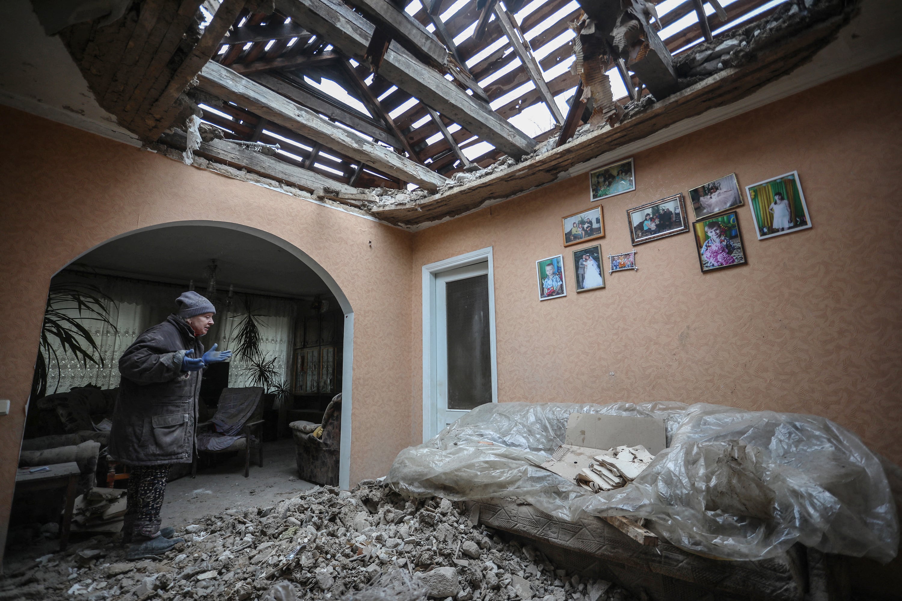 Una mujer intenta limpiar los escombros de su casa tras un bombardeo en Lugansk, Ucrania. 