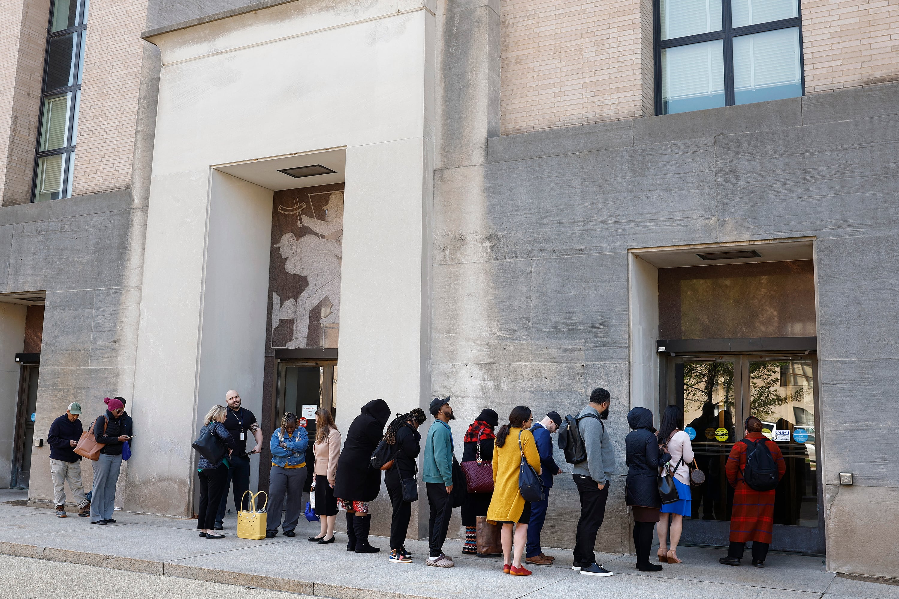 Empleados forman fila para ingresar al edificio de Salud y Servicios Humanos después del anuncio de los despidos.