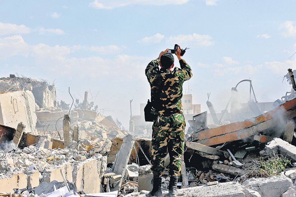 Un soldado sirio inspecciona las ruinas del edificio que era parte de un centro de investigación científica en Damasco.