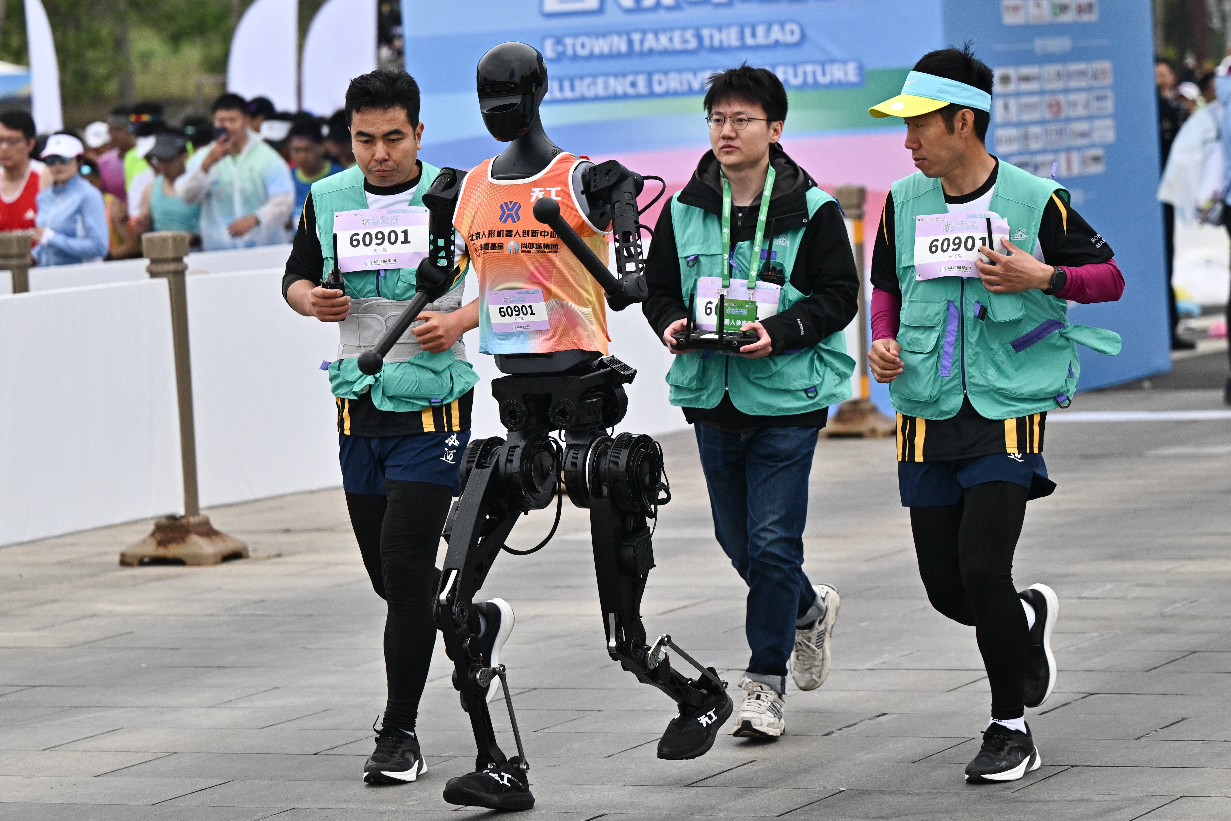 Un robot y sus ingenieros corren en la media maratón de robots humanoides