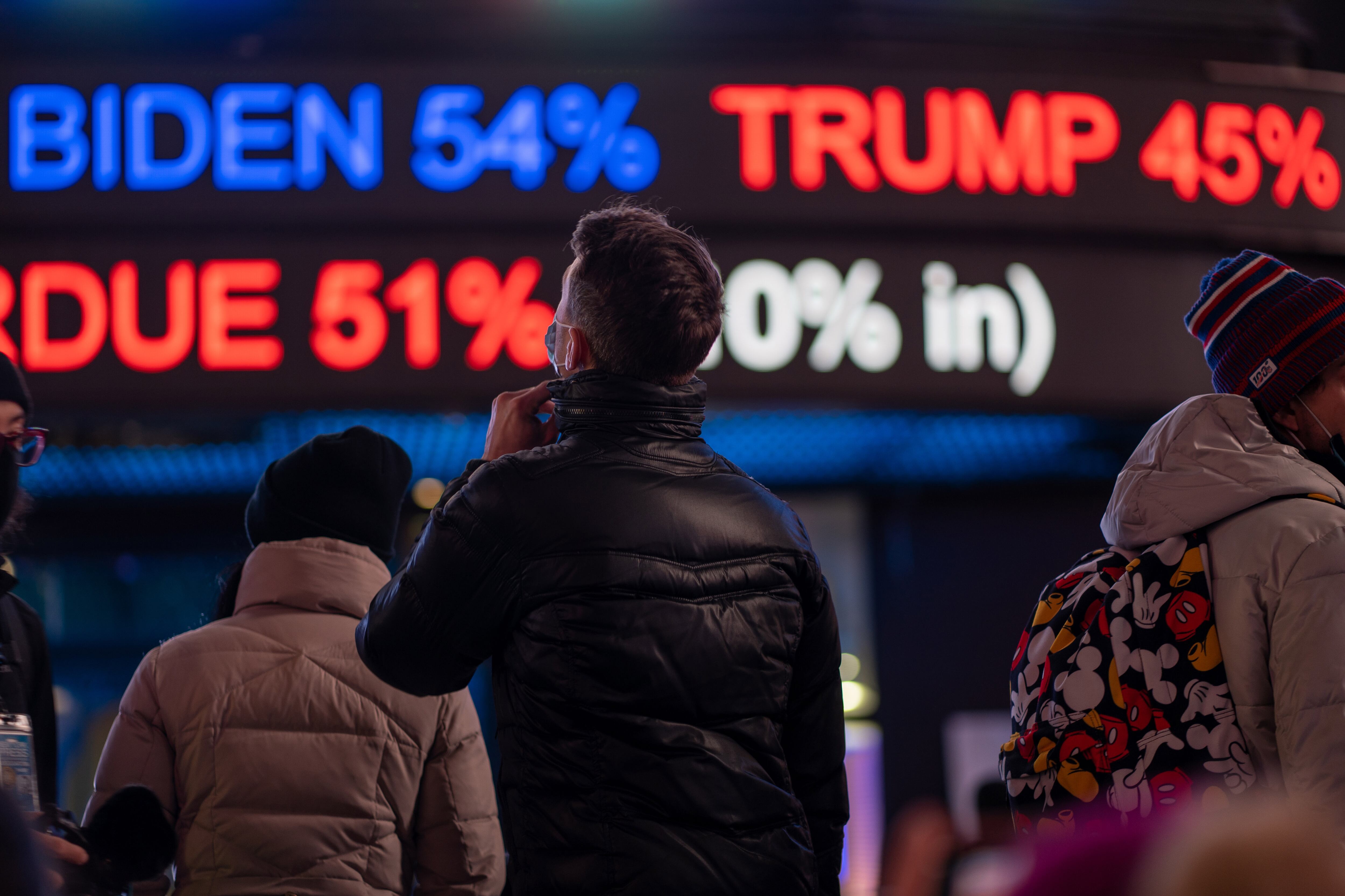 Gente mirando resultados electorales en los carteles de Times Square, Nueva York