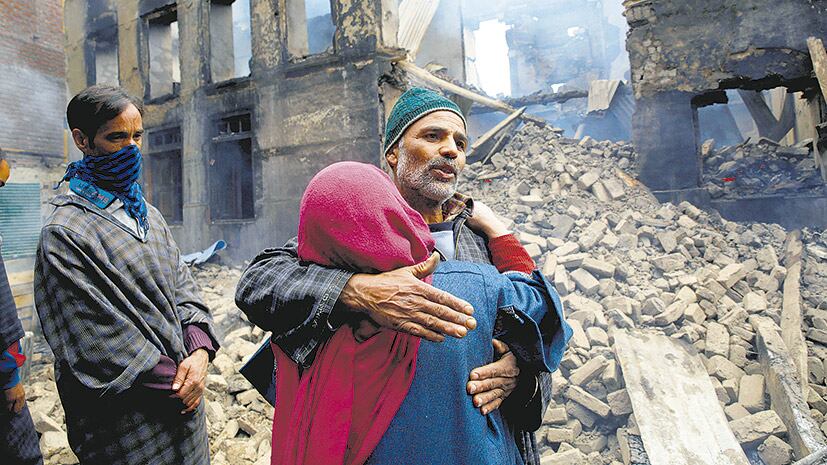Abrazo frente a un edificio destruido por el fuego cruzado en la Cachemira india.