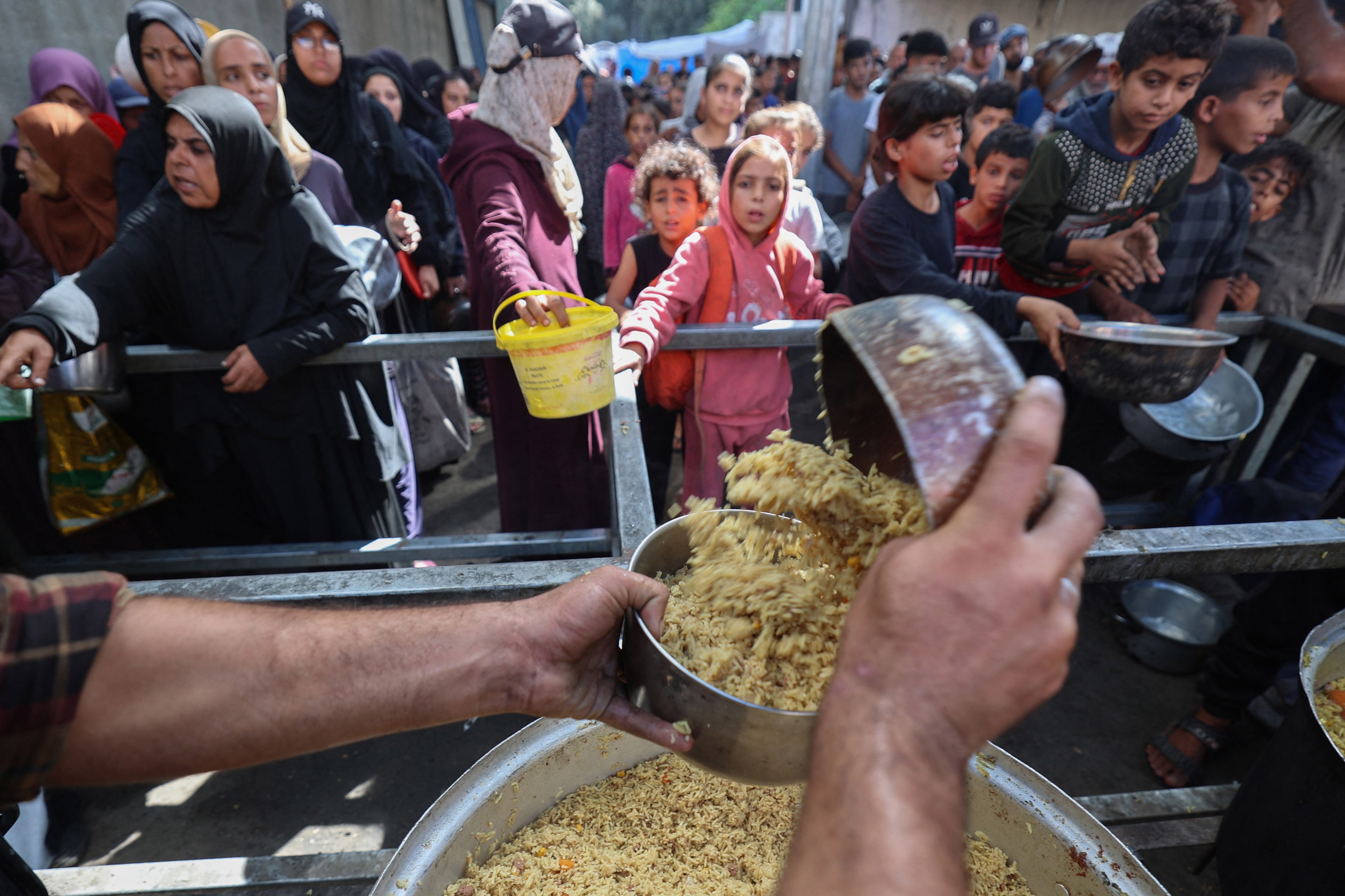 Niños palestinos reciben alimentos en un campo de refugiados de Gaza.