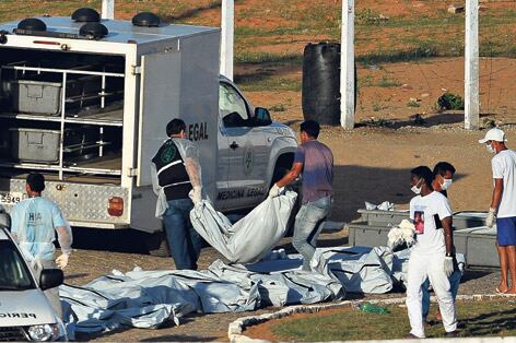 Personal sanitario retira los cuerpos de las víctimas de la pelea entre bandas en el penal de Alcacuz.