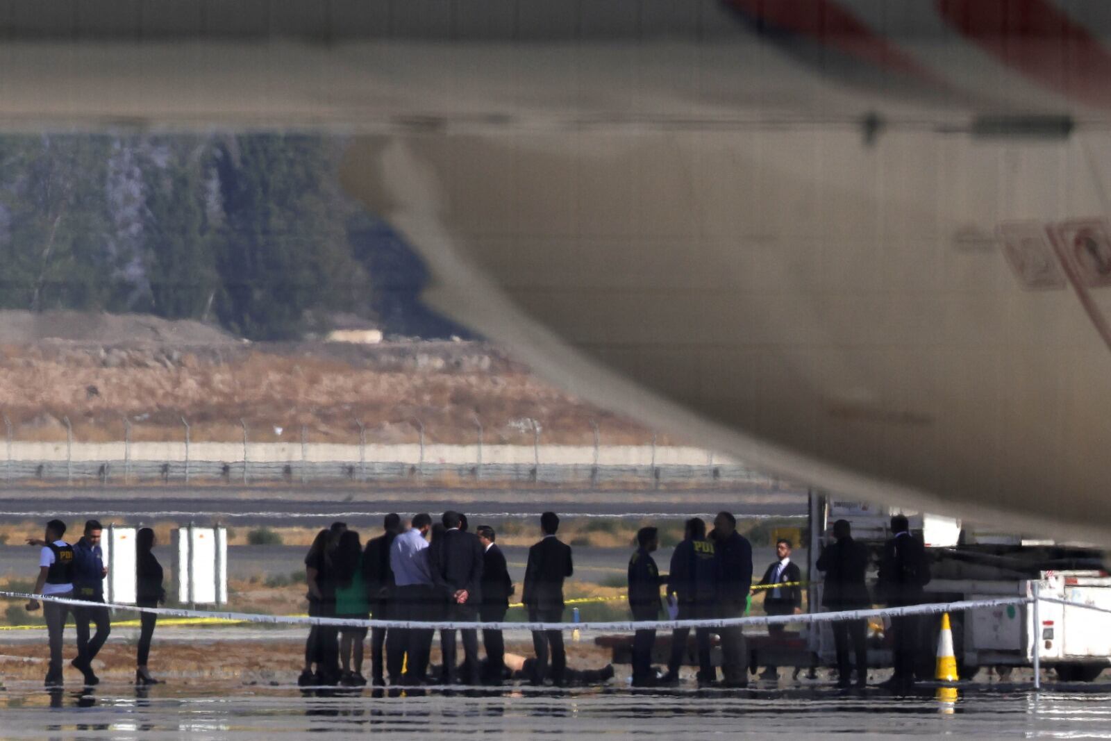 In.vestigadoresrodean un cadaver después deltiroteoen el aeropuerto de Santiago