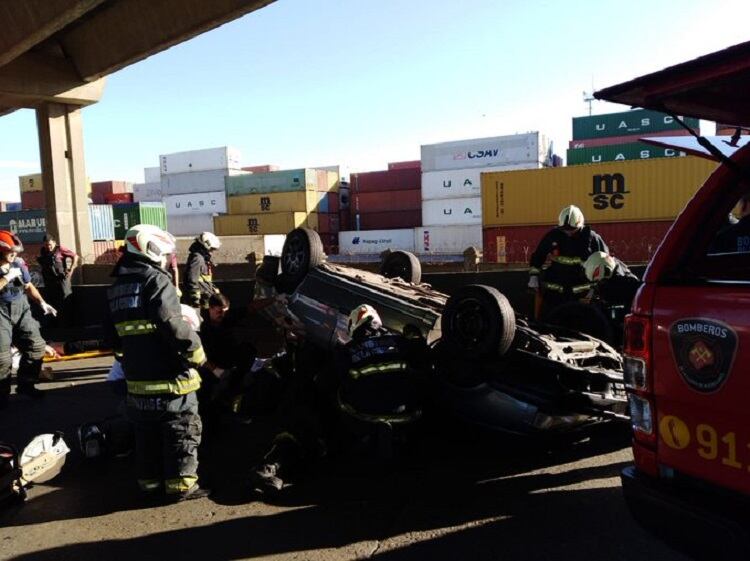 Bomberos revisan el auto tras el choque y vuelco en Puente Avellaneda.