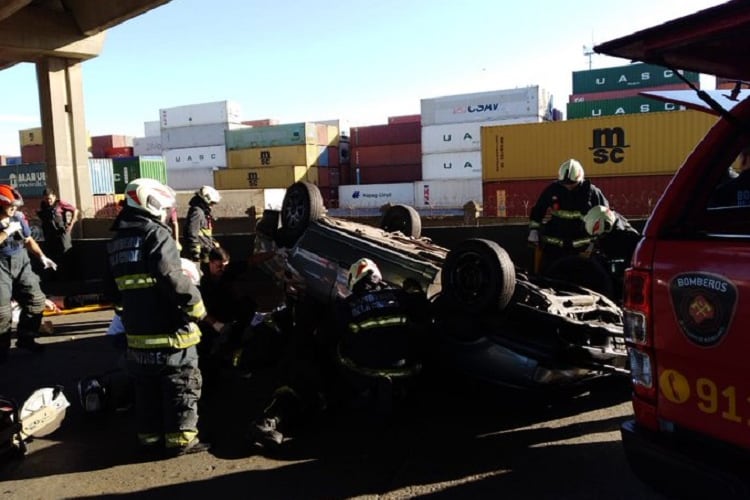 Bomberos revisan el auto tras el choque y vuelco en Puente Avellaneda.