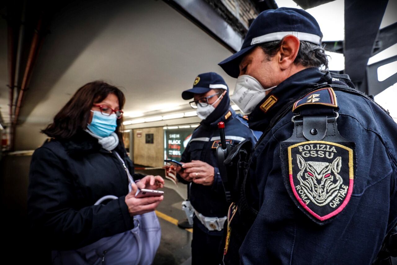 Policías italianos revisan el pase verde de una mujer en el centro de Roma. Foto2: Inspeccion de pases verdes en una para de autobuses en Brescia. (EFE)