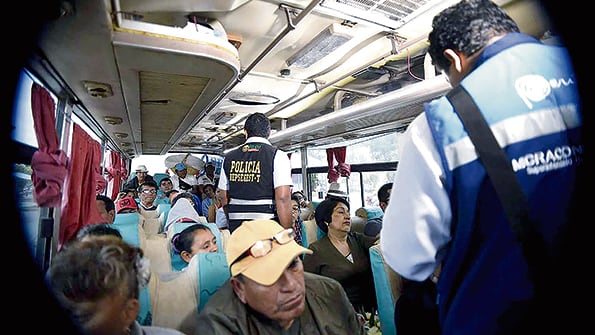 Agentes migratorios revisan documentos en un ómnibus en la localidad fronteriza de Tumbes.