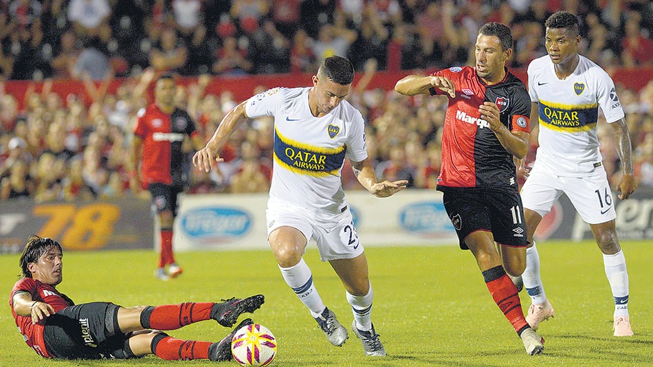 Marcone pasa entre Fornica y Maxi Rodríguez; Barrios observa la jugada.