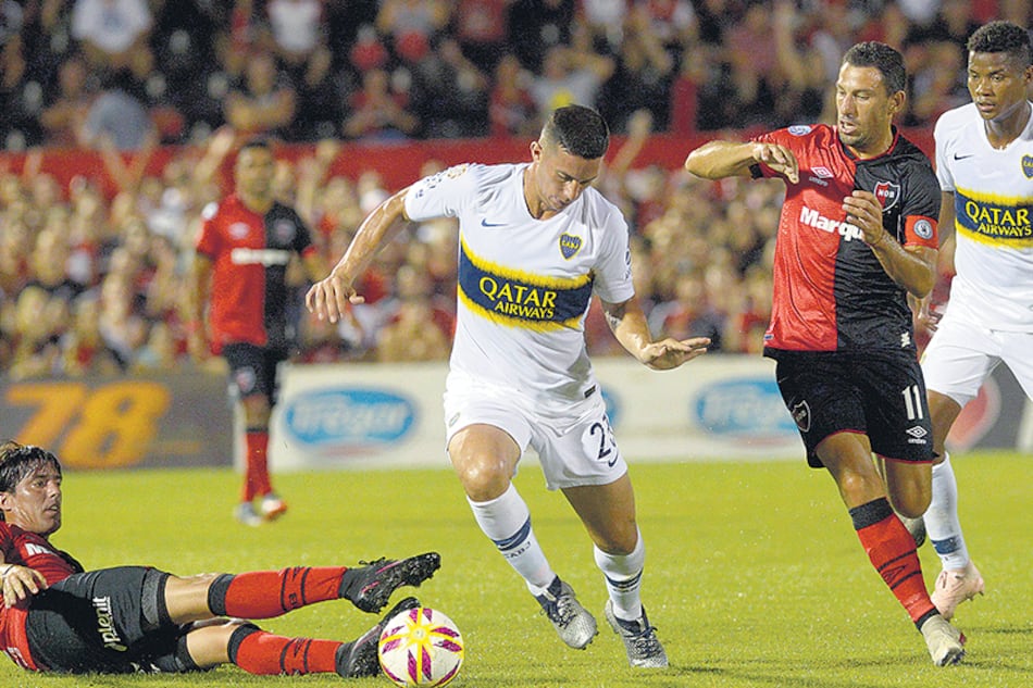 Marcone pasa entre Fornica y Maxi Rodríguez; Barrios observa la jugada.