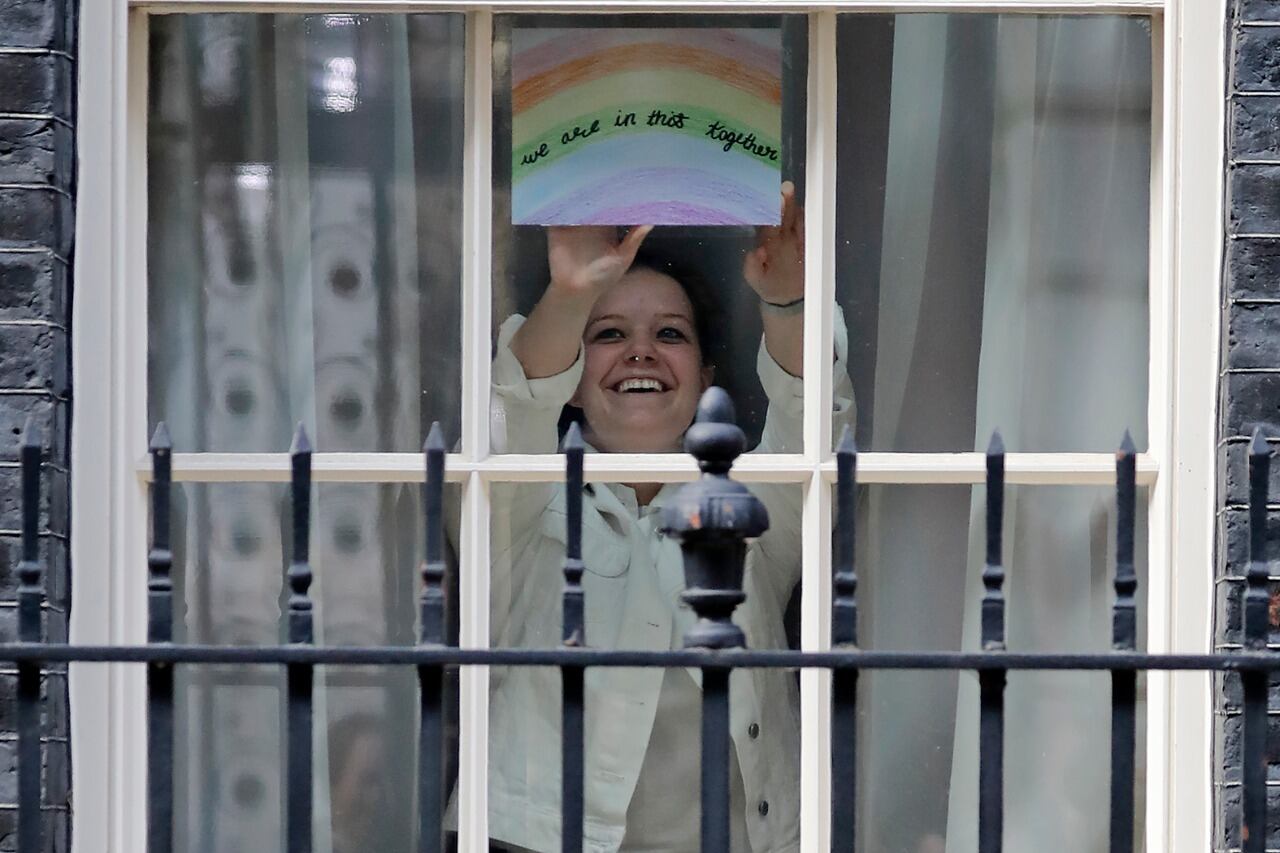 Una mujer muestra el arcoiris que se ve en las ventanas por estos días de encierro; este aparece desde la residencia oficial del primer ministro.