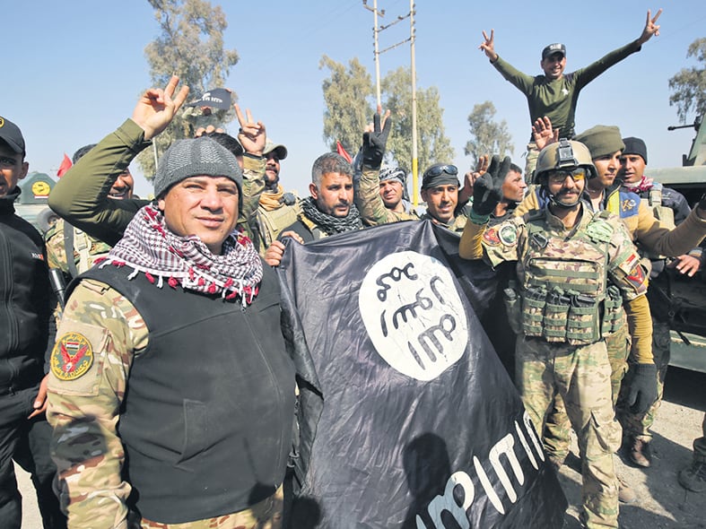 Fuerzas iraquíes muestran una bandera del EI al festejar su entrada al aeropuerto. 