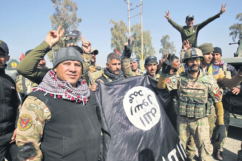 Fuerzas iraquíes muestran una bandera del EI al festejar su entrada al aeropuerto.