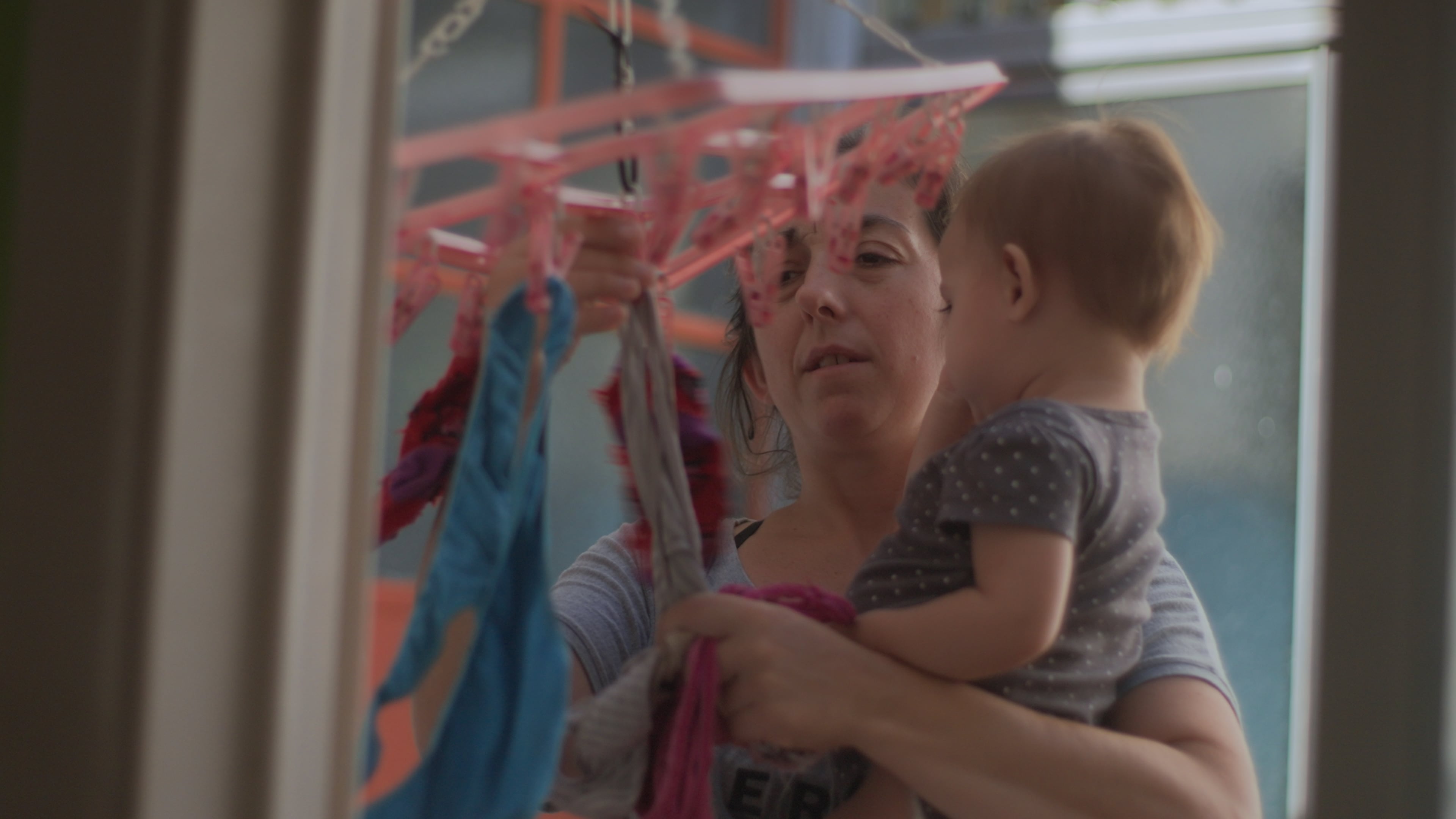 Colgar la ropa con un bebé en brazos, una imagen que de tan arquetípica esconde su esfuerzo.