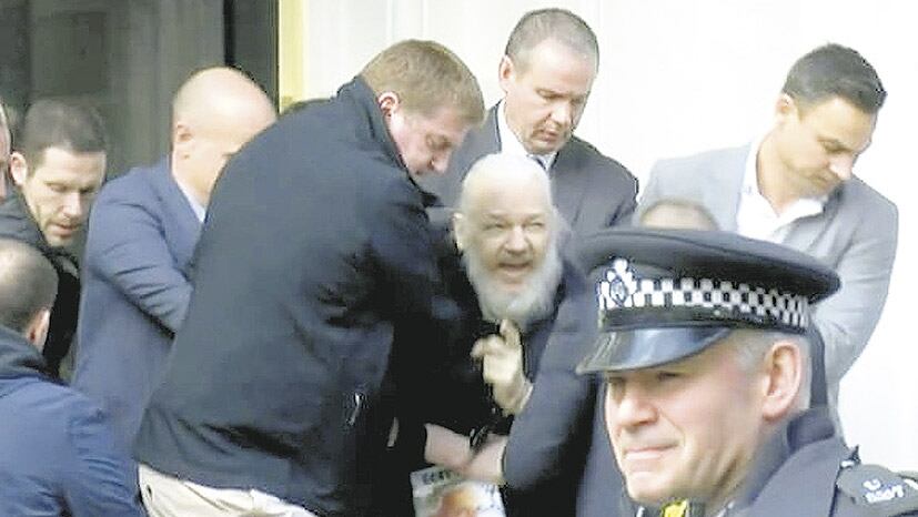 Assange es arrastrado por policías a un patrullero en la entrada de la embajada de Ecuador.