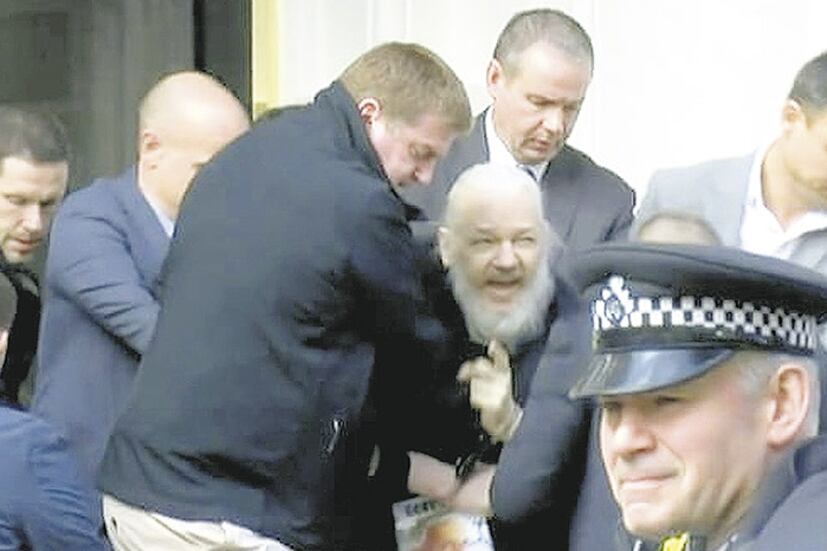 Assange es arrastrado por policías a un patrullero en la entrada de la embajada de Ecuador.