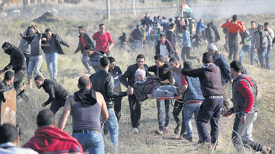 Manifestantes palestinos cargan con un herido durante un enfrentamiento con soldados israelíes en la frontera este de Gaza.