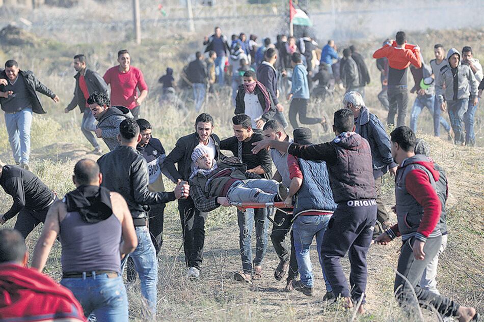 Manifestantes palestinos cargan con un herido durante un enfrentamiento con soldados israelíes en la frontera este de Gaza.