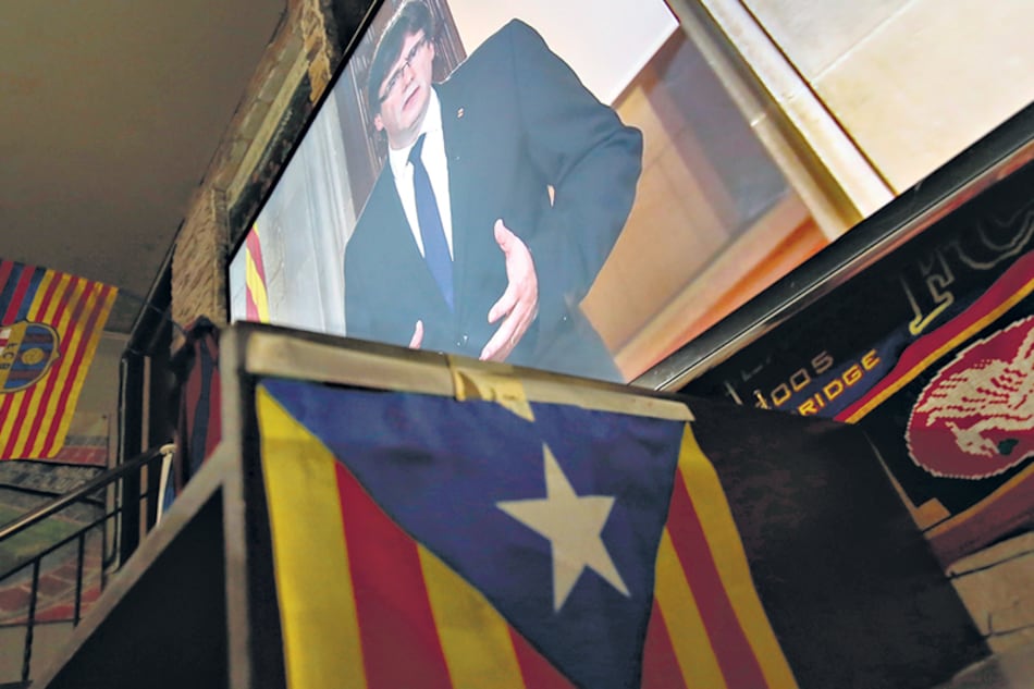 La pantalla gigante de un bar de Barcelona muestra la imagen de Puigdemont dando un mensaje a los catalanes.