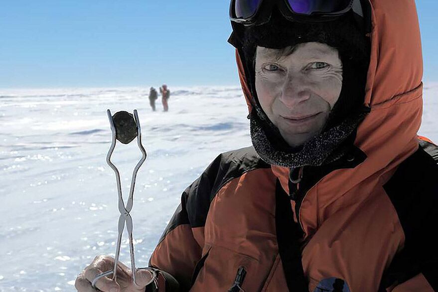 Oppenheimer feliz con una gema negra encontrada en el desierto blanco antártico.