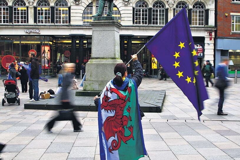 Una manifestante protesta contra la puesta en marcha del Brexit con las banderas de la UE y de Gales.