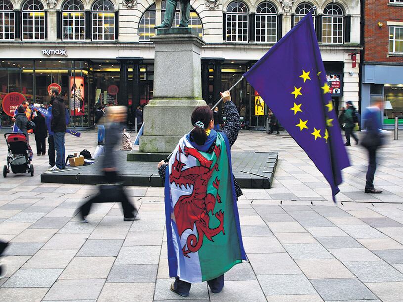 Una manifestante protesta contra la puesta en marcha del Brexit con las banderas de la UE y de Gales.
