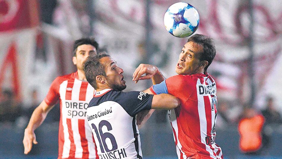 Belluschi, autor del tanto de San Lorenzo, disputa el balón con Desábato.