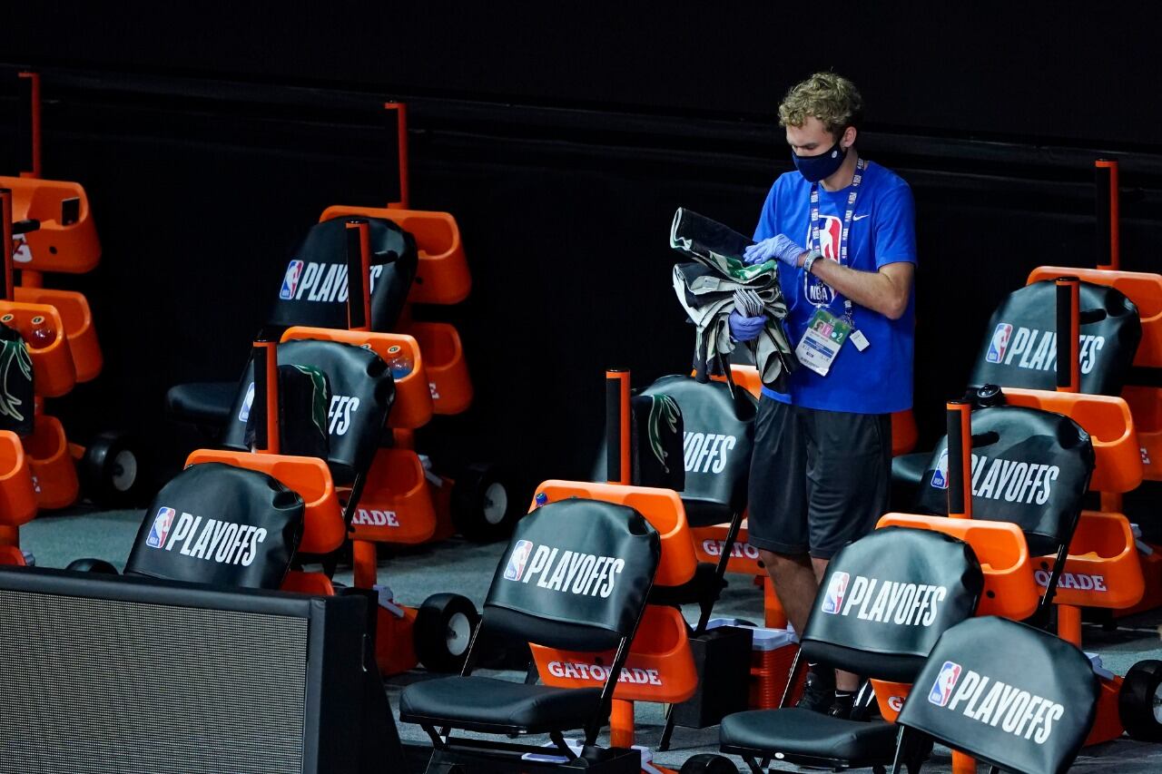 Un empleado asea el banco de suplentes tras la suspensión del partido de Milwaukee - Orlando 