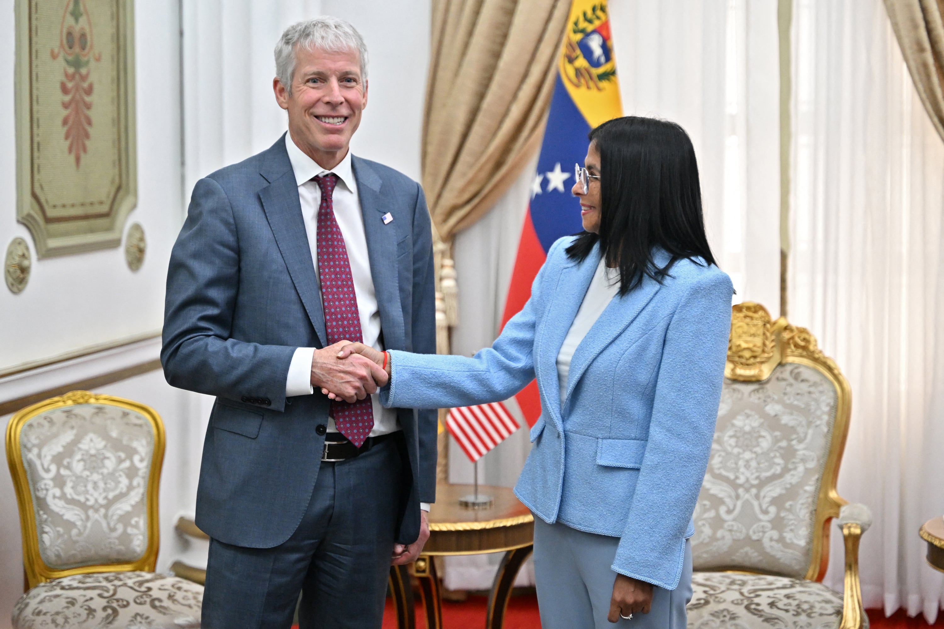US Secretary of Energy Chris Wright (L) shakes hands with Venezuela's acting president Delcy Rodriguez