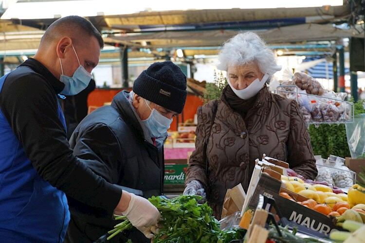 Gente con barbijos en un mercado de frutas en Venecia.