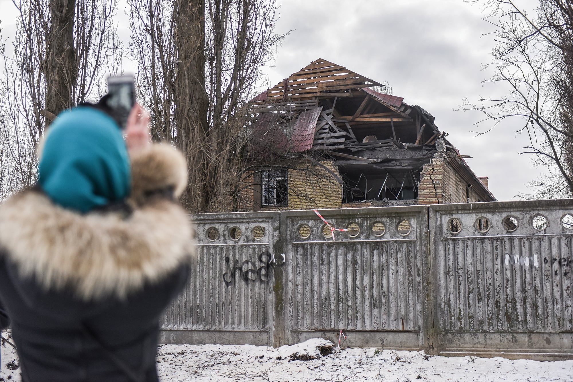 Una mujer le saca una foto en Kiev a uno de las residencias dañadas por un dron.