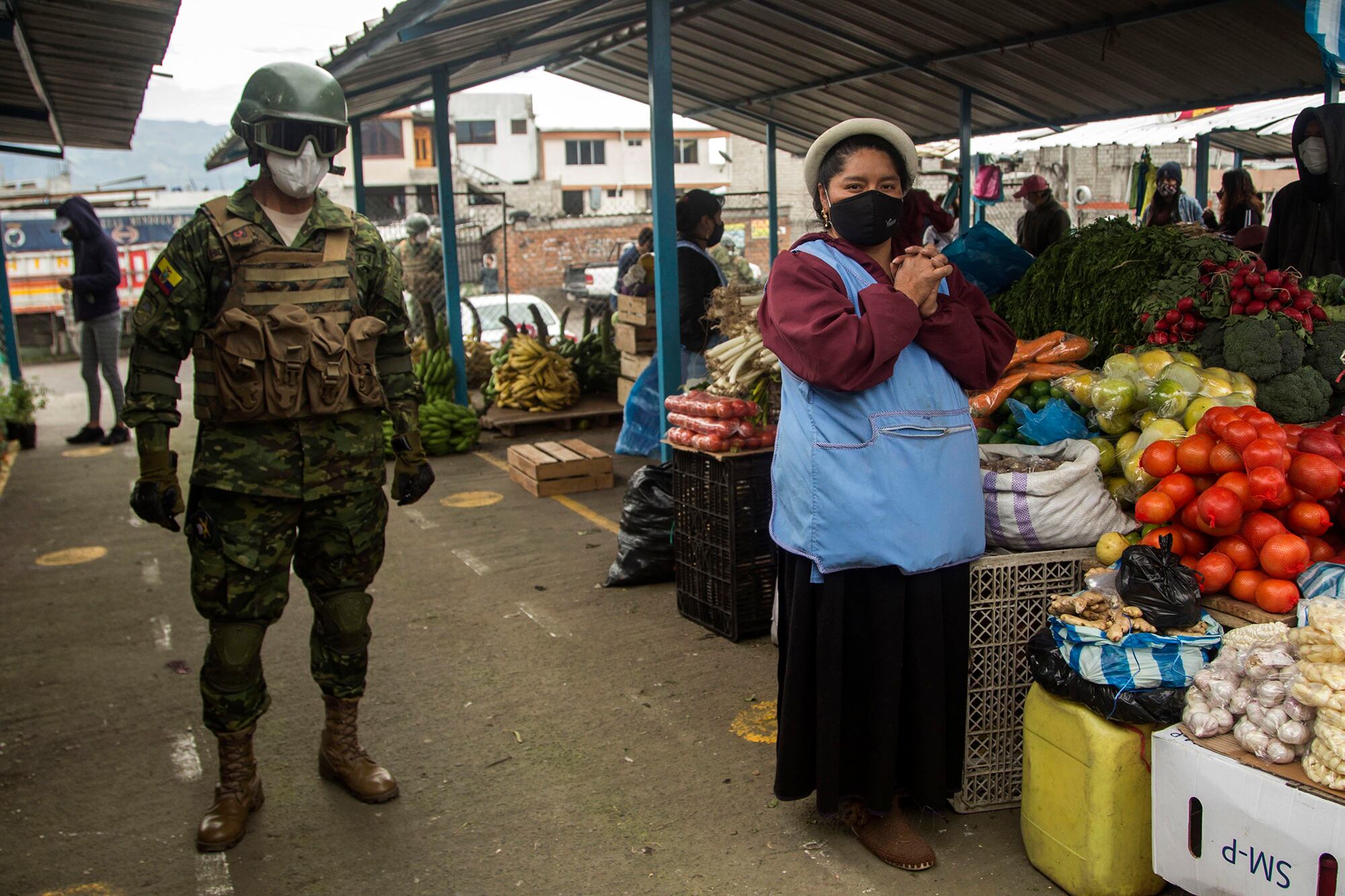 Un soldado patrulla un mercado en Quito para asegurarse de que se cuplan las restricciones.
