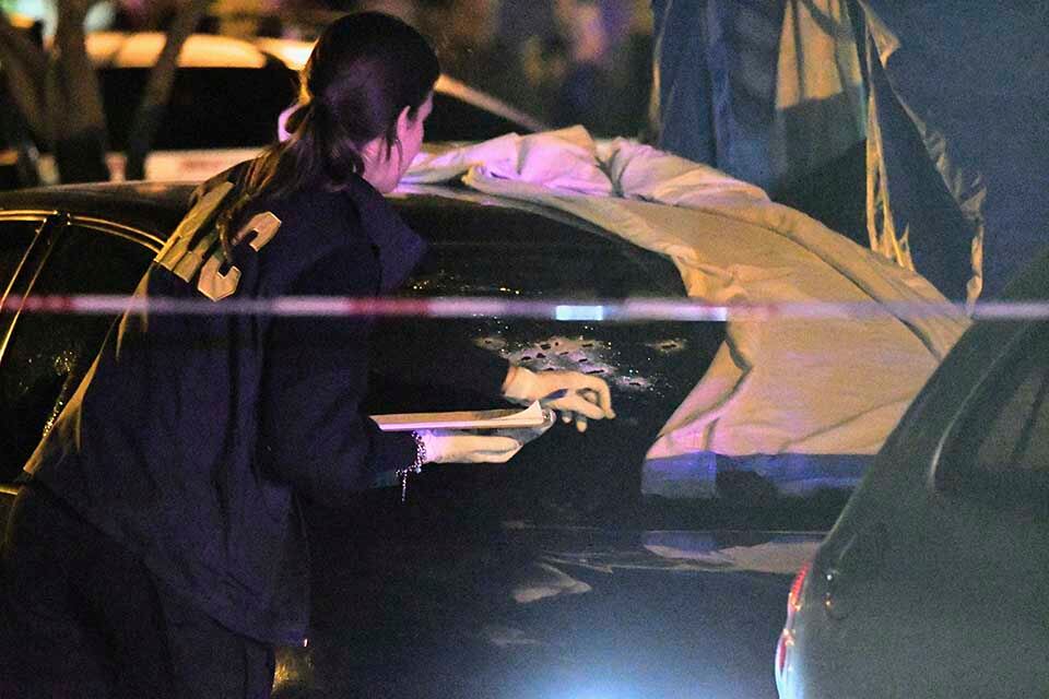 Peritos trabajando sobre el auto acribillado.