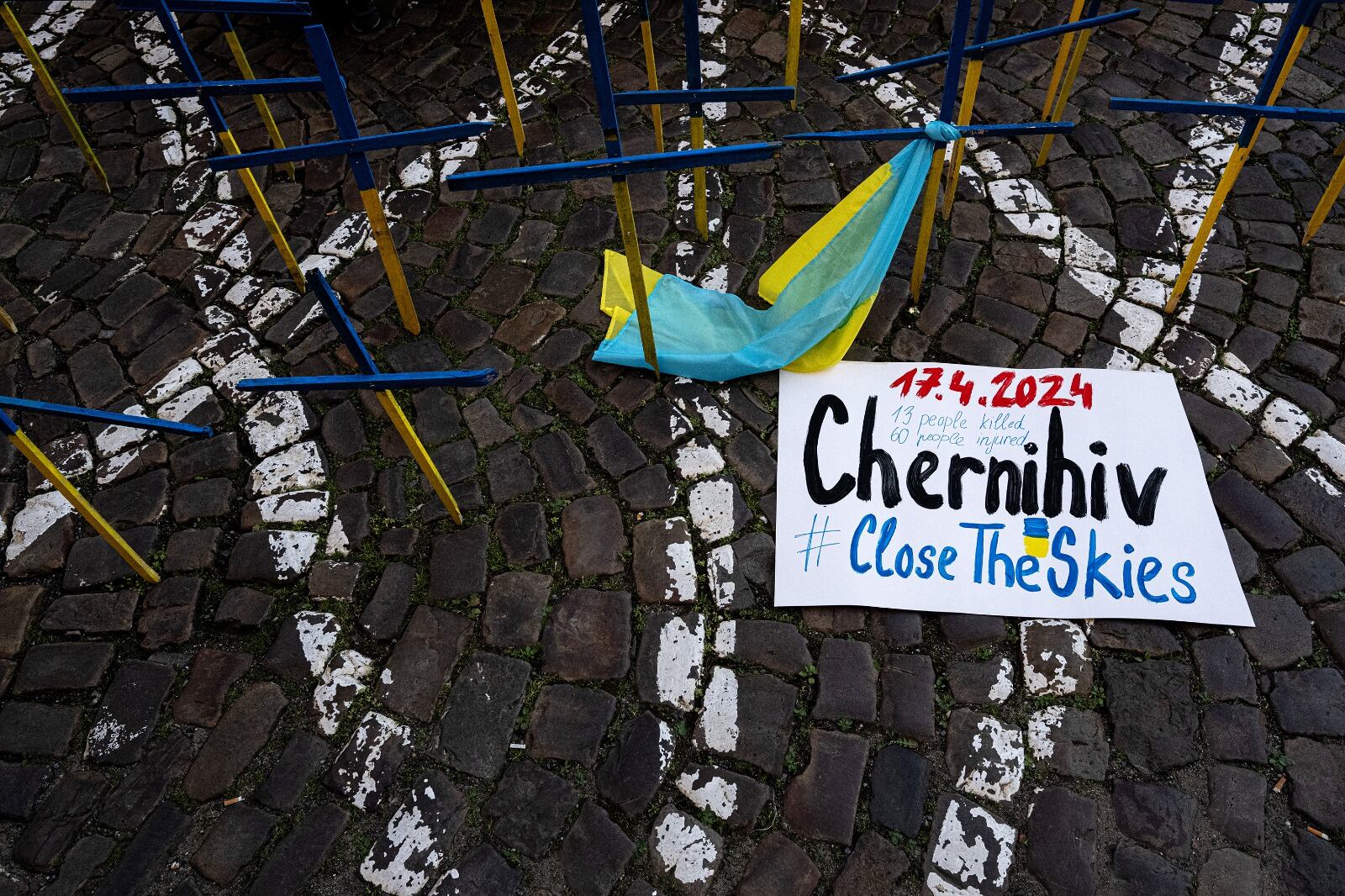 "Chernigov, cierren los cielos" se ve junto a cruces de madera con los colores nacionales ucranianos frente a la embajada de EE.UU.en Praga. 