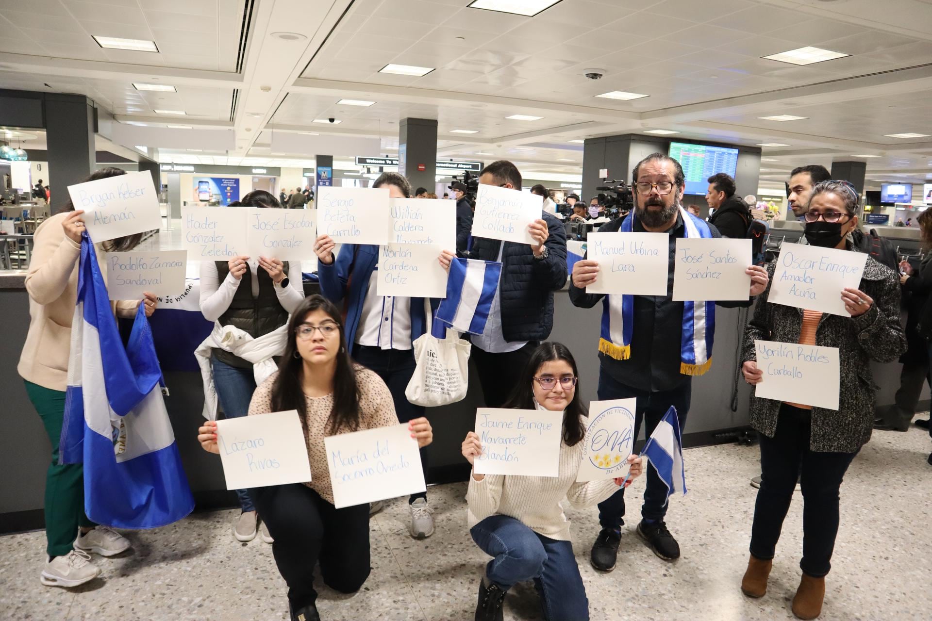 Varias personas sostienen hojas con los nombres de los presos políticos nicaragüenses, expulsados de su país, mientras esperan su llegada en el aeropuerto de Dulles, Virginia (EE.UU.) Foto: Octavio Guzmán/EFE