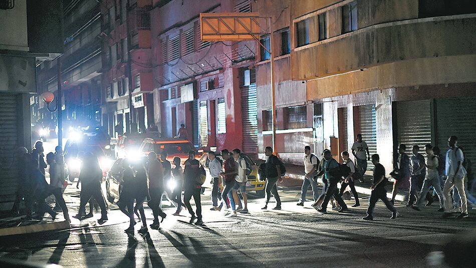 Un grupo de personas cruza una calle de Caracas a oscuras debido al apagón general.