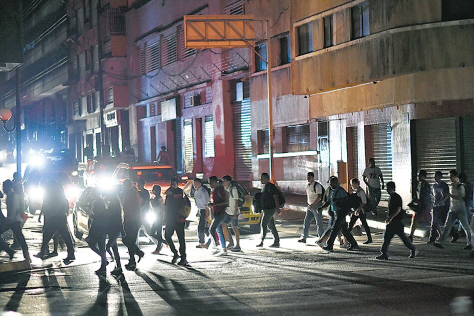Un grupo de personas cruza una calle de Caracas a oscuras debido al apagón general.