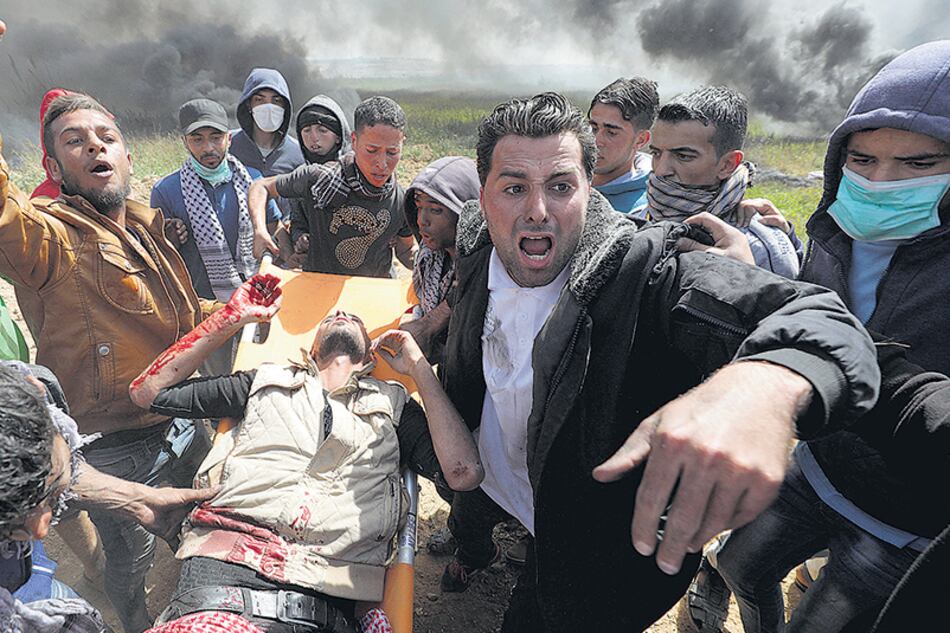 Manifestantes palestinos transportan en camilla a un activista herido en la frontera con la Franja de Gaza.